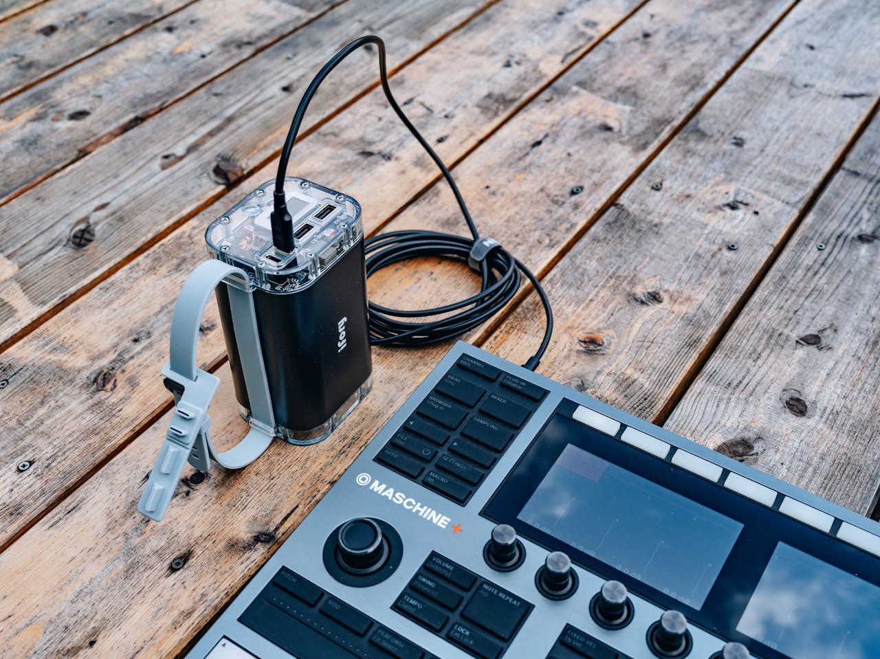 Music equipment setup on rustic wooden floor, showcasing a sound mixer and cables.